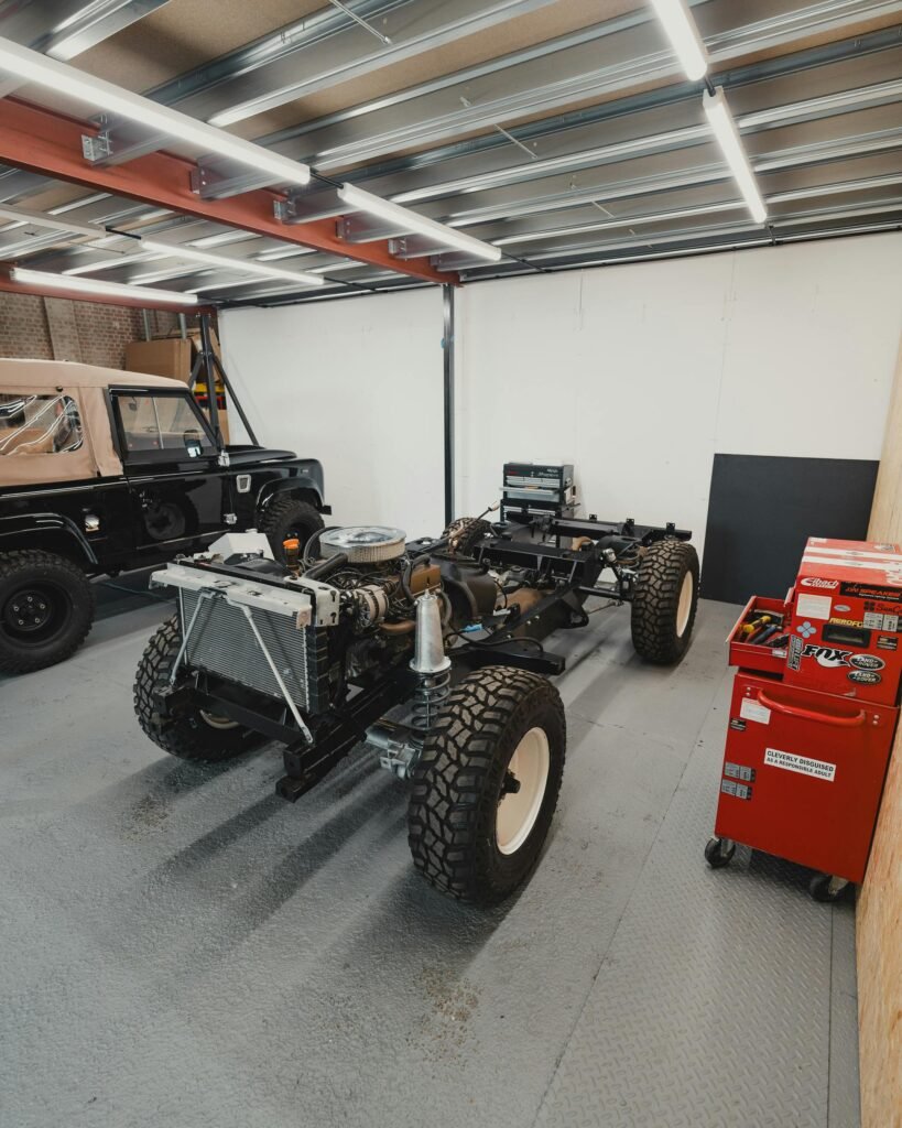 A Land Rover undergoing restoration in a well-organized workshop garage setting.