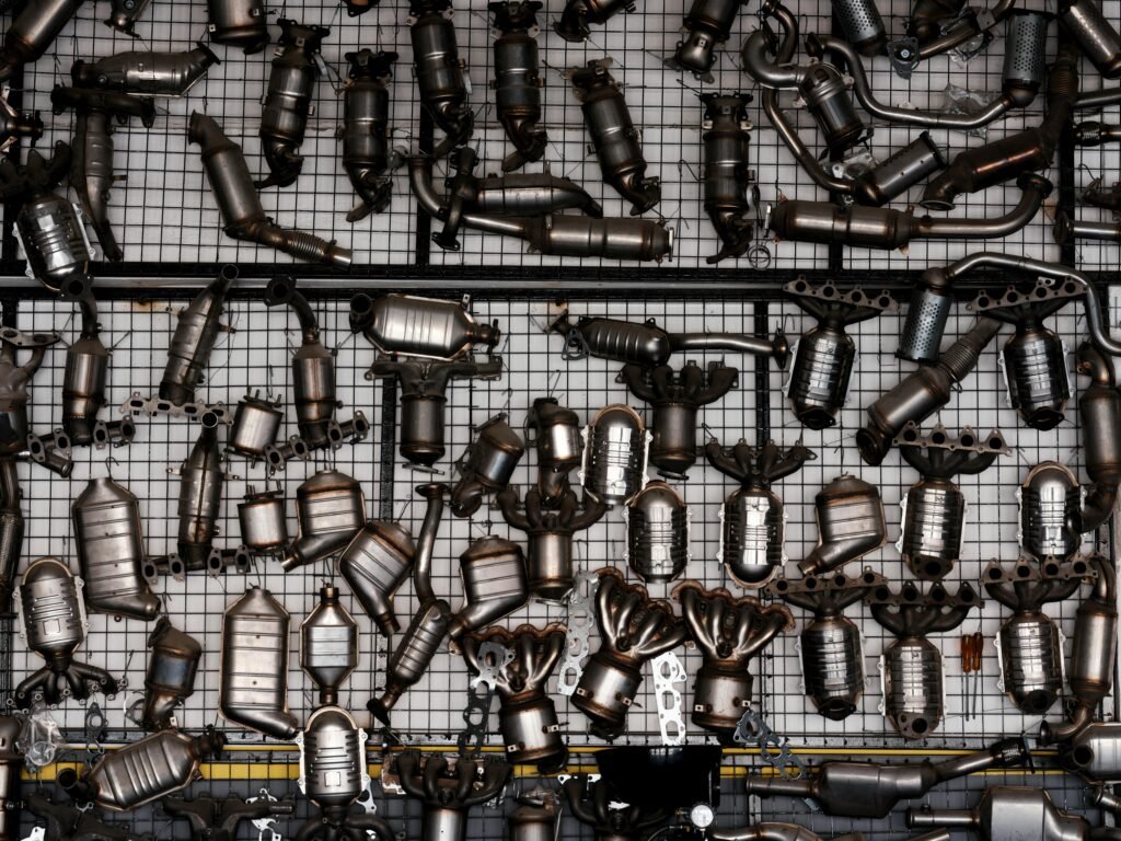 An array of automotive exhaust parts displayed on a grid wall in an industrial garage setting.
