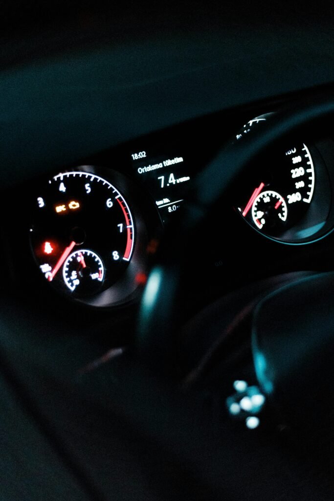 A modern car dashboard showing illuminated gauges and indicators at night.