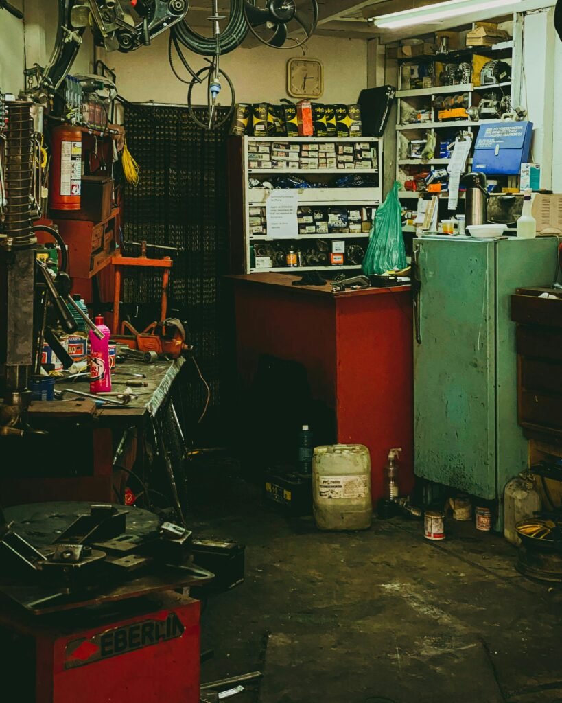 A cozy, cluttered auto repair workshop filled with tools, equipment, and parts, showcasing an active workspace.