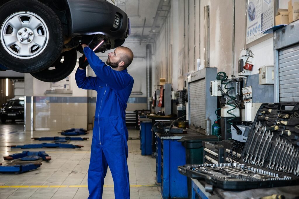 Mechanic inspecting a raised car in an auto workshop for maintenance and repair services.