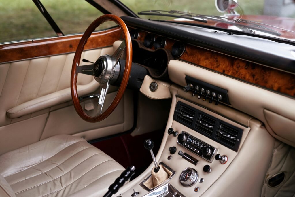 Close-up of a vintage car interior featuring wooden trim, leather upholstery, and a classic dashboard.