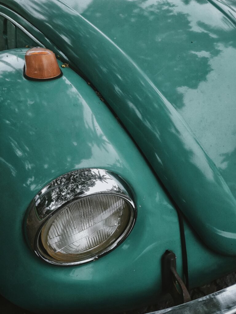 Detailed photo of a classic turquoise Volkswagen Beetle's headlight, showcasing vintage charm.